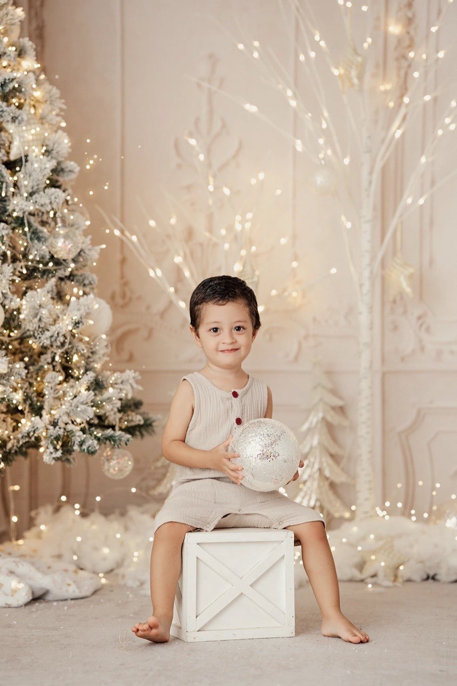 Niño sentado en un cajón blanco con una esfera